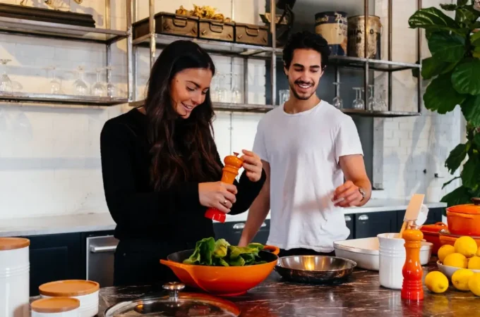 Two people cook dinner in a clean, bright, healthy kitchen