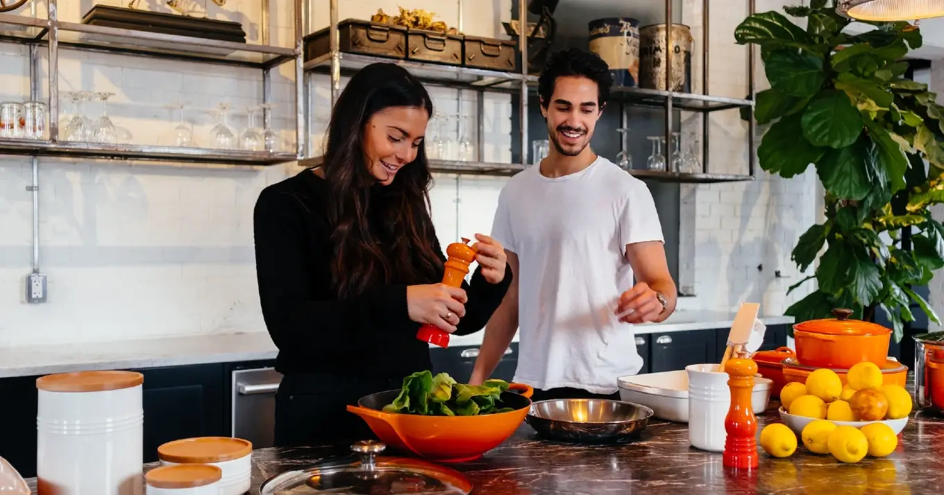 Two people cook dinner in a clean bright healthy kitchen.